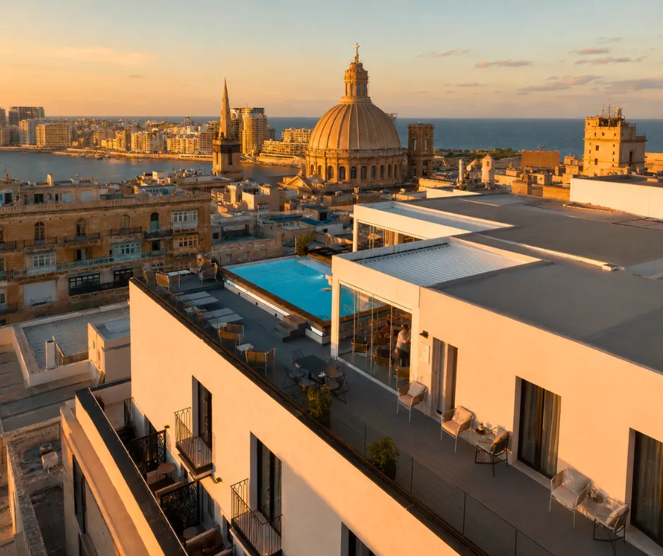 Rooftop pool at sunset overlooking the Carmelite dome and Sliema from a The Embassy Valletta hotel