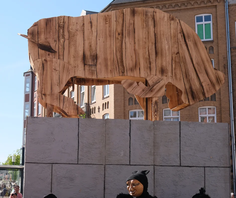 A wooden bull effigy displayed on a plinth in a Danish city square ahead of Aalborg Karneval's Burning of the Bull