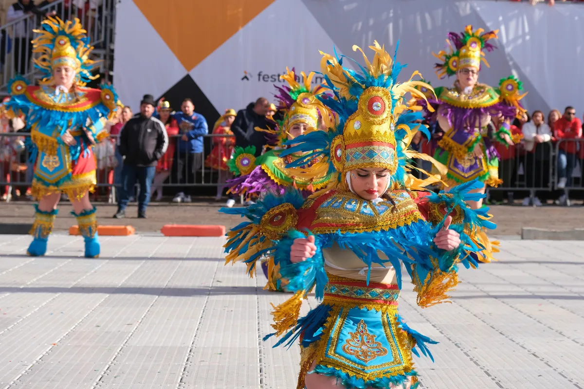 Dancer in a blue and gold feathered costume performing at Malta Carnival, with Valletta hotels a short walk from the parade route