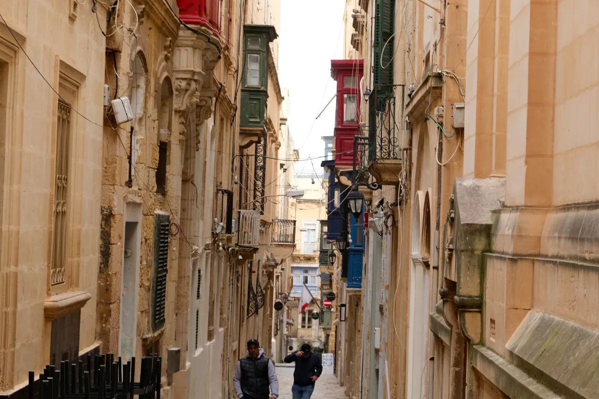 Narrow Valletta street lined with traditional coloured balconies near hotels for Malta Carnival