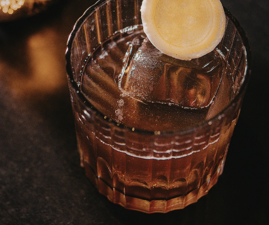 Dark rum cocktail served over ice with a citrus garnish in a glass.