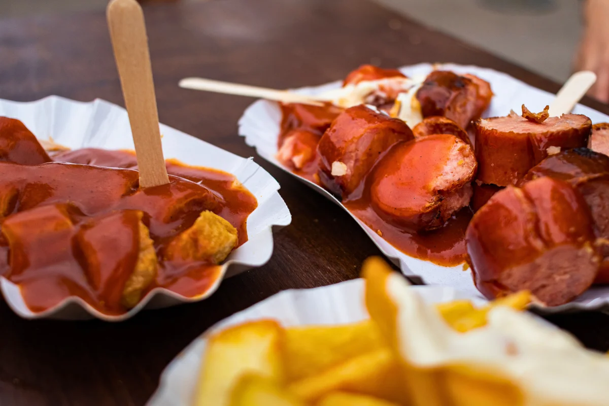 Paper trays of currywurst with curry sauce and fries, a classic Berlin street food to try on a local food tour