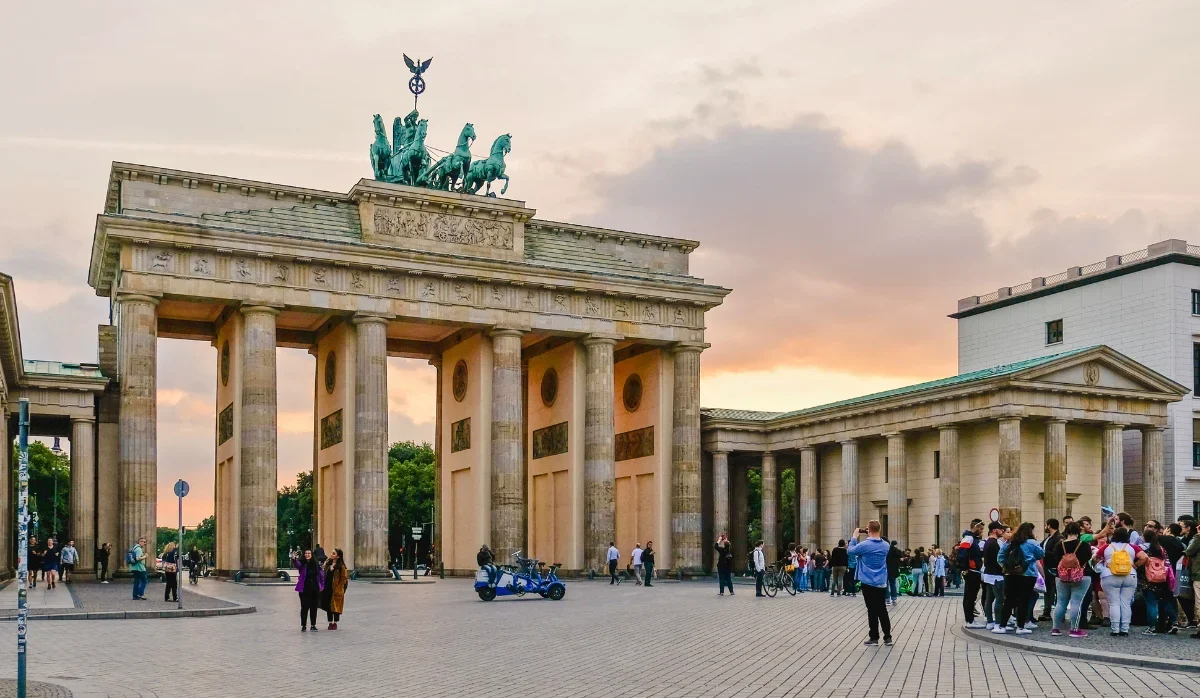 Visitors gathered at the Brandenburg Gate in Berlin at sunset, a key stop on a guided walking tour during Carnival weekend