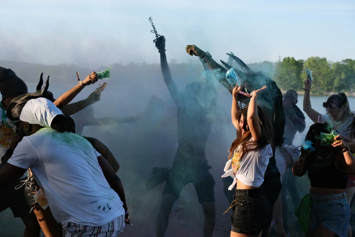 Revelers throwing clouds of blue and green powder into the air during J'ouvert at Vienna Carnival