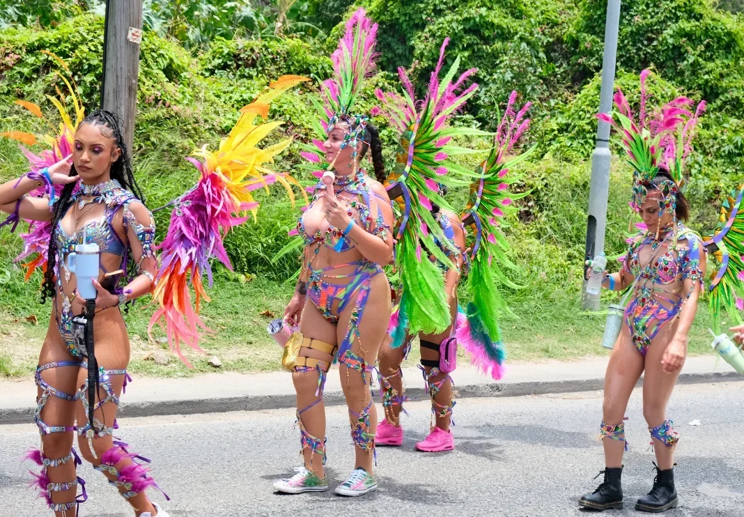 Masqueraders in gem-covered costumes with pink and green feather backpacks on the road at SXM Carnival, one of the Caribbean Carnivals 2027