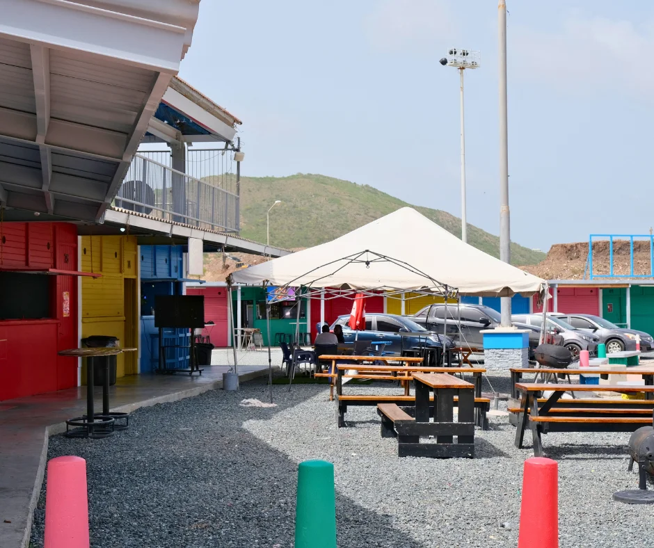 Inside the Jocelyn Arndell Festival Village in Philipsburg with colorful vendor booths, seating areas and the SXM Carnival event grounds