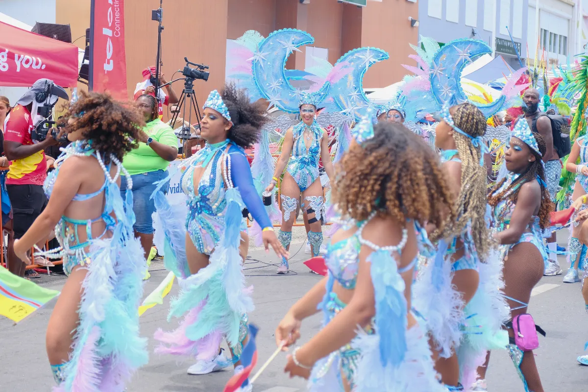 Masqueraders in matching pale blue and pink costumes dancing together as their section moves along the road at St. Maarten Carnival