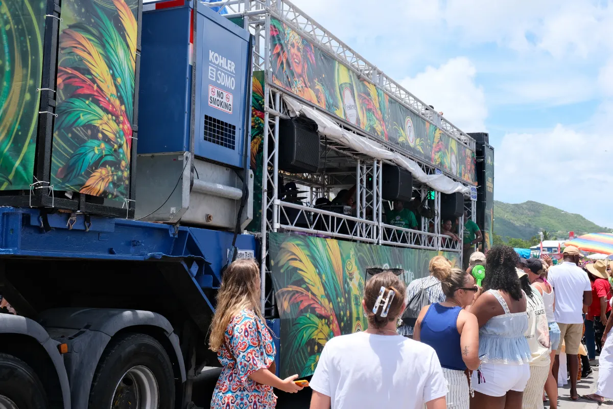 Crowd gathered around a music truck rigged with speakers during a Caribbean Carnival parade