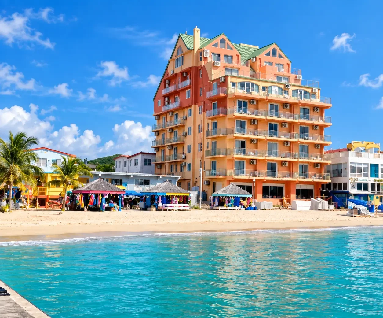 Beachfront hotel and colorful shops along the coast of St. Maarten, showing a beach accommodation option for where to stay for SXM Carnival