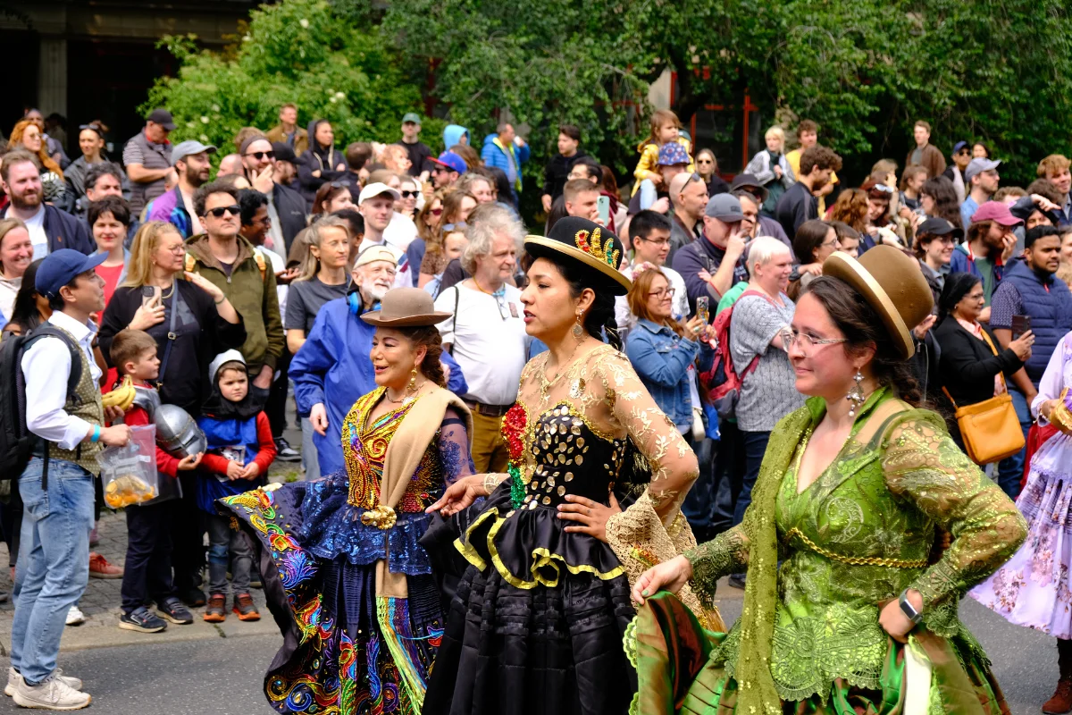 Performers in colorful traditional costumes parade through Berlin Carnival as spectators gather along the street