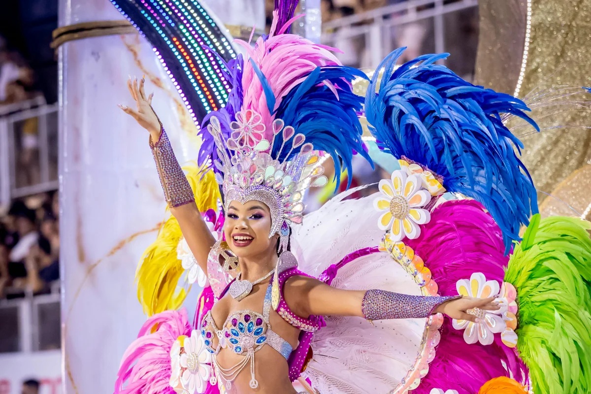Carnival performer at the Carnival of Encarnación in Paraguay wearing a pink and gold feathered costume and ornate headdress