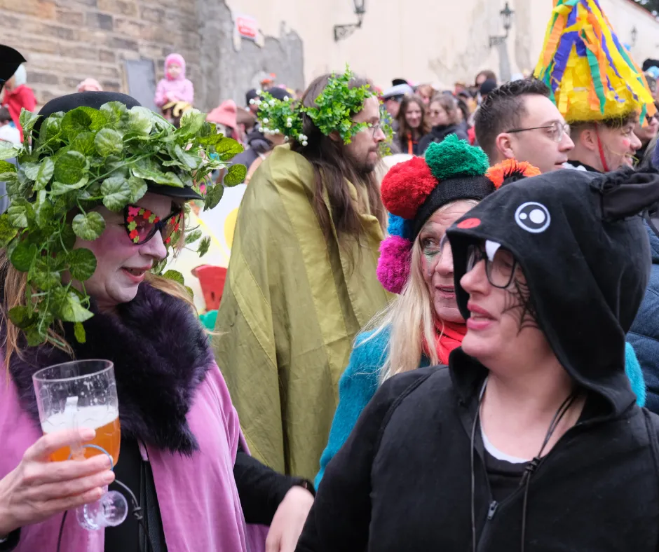 Revelers in colourful costumes enjoying Czech beer during Masopust celebrations in Prague
