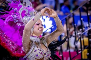 Dancer in a pink feathered headdress and jeweled costume performing at the Sambódromo during Encarnación Carnival
