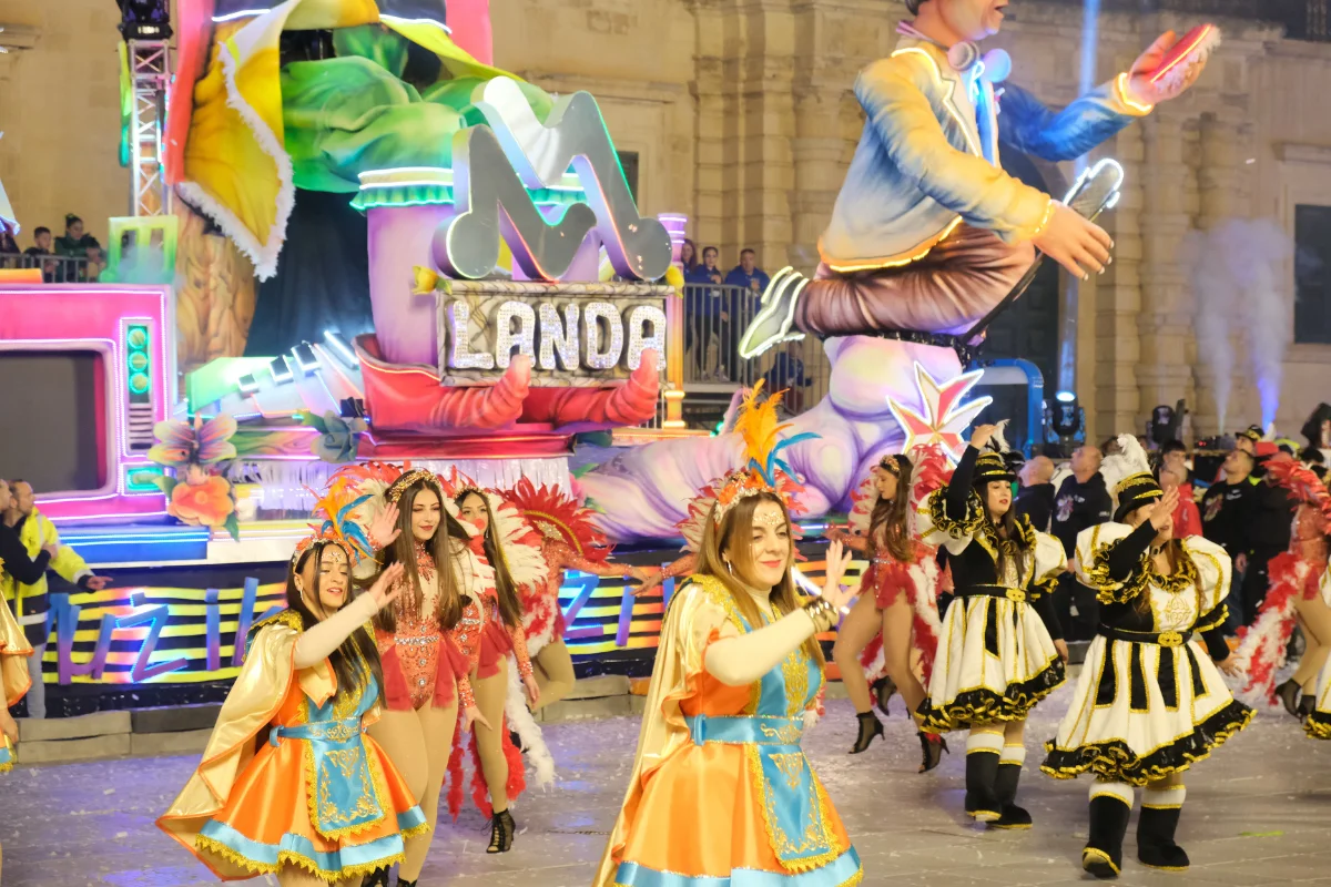 Dancers performing in front of the illuminated King Carnival float by Landa Carnival Company at Malta Carnival in Valletta