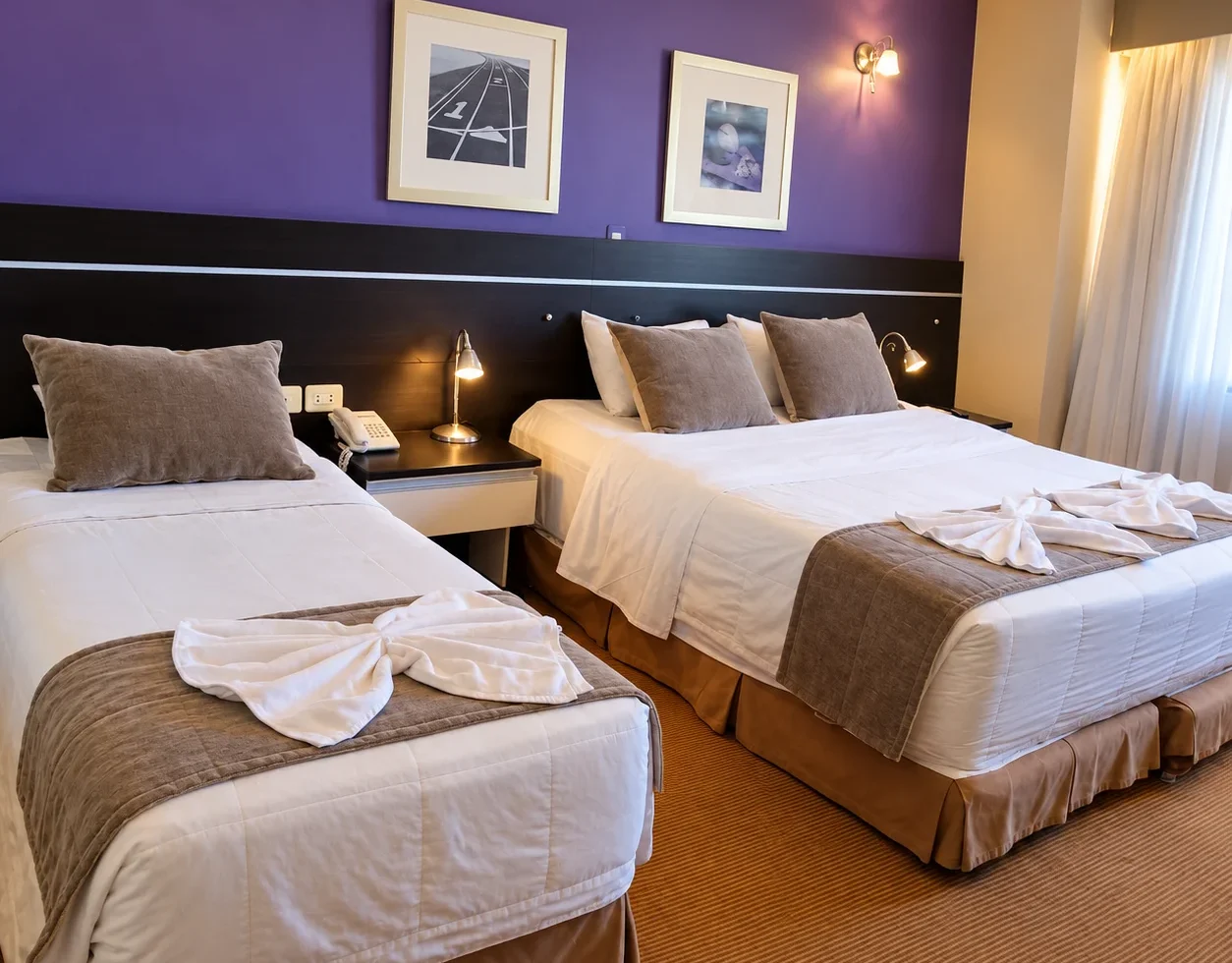 Hotel room at Le Club Resort Hotel featuring one double bed and one single bed with white linens brown accents and purple walls